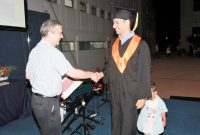 The Dean on stage, conferring the diploma to a graduate student, shaking hands